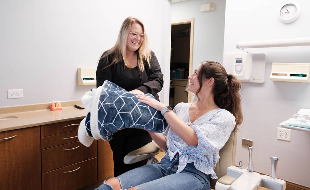 Woman taking a blanket from dental assistant